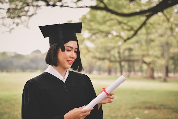 Glimlachende jonge vrouw met diploma in het park