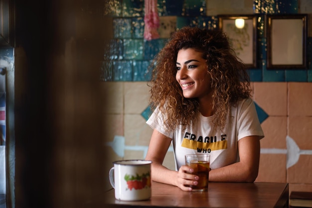 Glimlachende jonge vrouw met een drankje in een restaurant