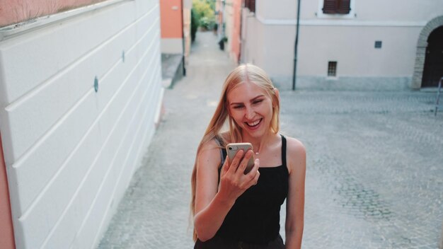 Foto glimlachende jonge vrouw met mobiele telefoon buiten