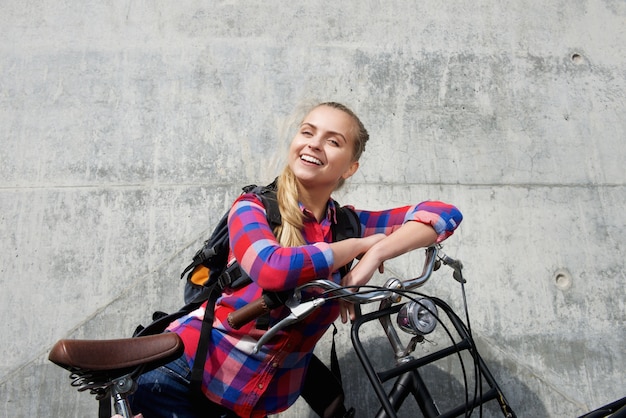 Glimlachende jonge vrouw met rugzak en fiets