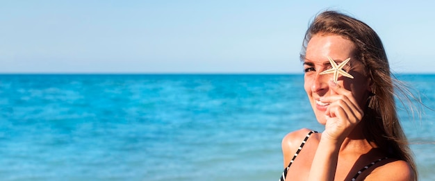 Glimlachende jonge vrouw sluit haar oogzeester op het strand Banner