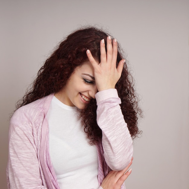 Glimlachende jonge vrouw tegen de muur.