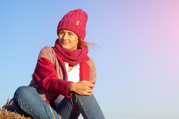 Foto glimlachende jonge vrouw zit tegen een heldere hemel