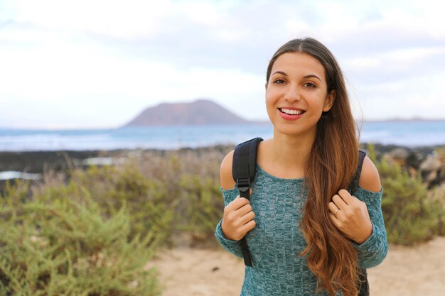 Glimlachende jonge vrouwelijke backpacker die in het Eiland van Fuerteventura, Spanje wandelt