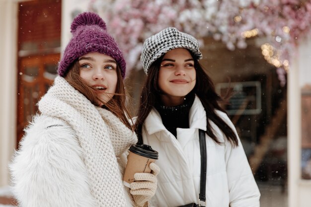 Glimlachende jonge vrouwen die warme de winterkleding dragen chatten