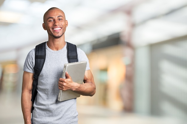 Glimlachende jonge zwarte student met laptop