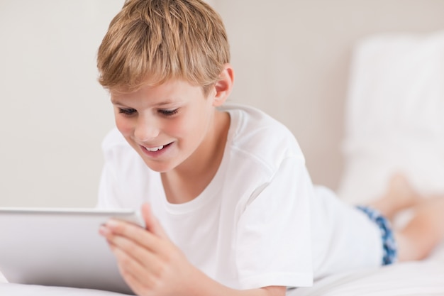 Glimlachende jongen die een tabletcomputer met behulp van