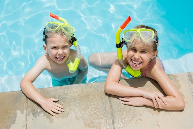 Glimlachende jongen en meisje die aan de kant van het zwembad ontspannen