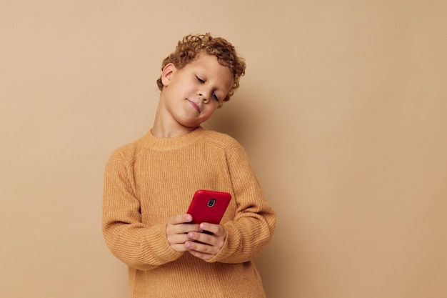Glimlachende jongen in een trui met een telefoon in zijn handen communicatie