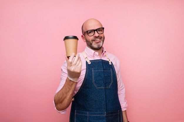 Glimlachende kale volwassen man met koffie in recyclebare kartonnen beker