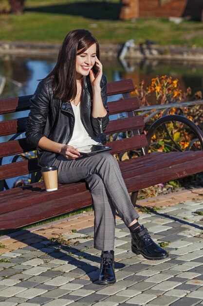 Glimlachende Kaukasische vrouw met mobiele telefoonzitting in park