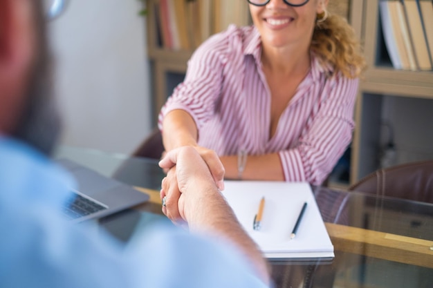 Glimlachende kaukasische vrouwelijke hr-manager handdruk huren mannelijke kandidaat bij sollicitatiegesprek maak een goede eerste indruk gelukkig gemengd ras klant schud de hand van bankmakelaar respect zakelijke overeenkomst conceptxA