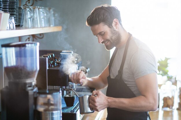 Glimlachende kelner die kop van koffie maakt