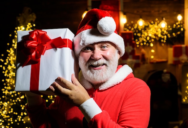 Glimlachende kerstman houdt huidige doos vast, kerstman houdt nieuwjaarscadeau kerstversiering vrolijk