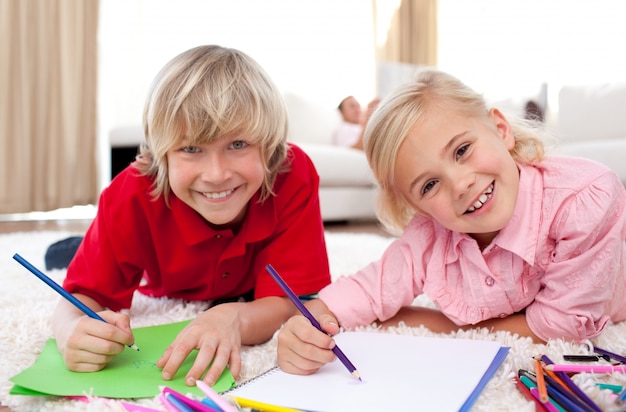 Glimlachende kinderen die liggend op de vloer trekken