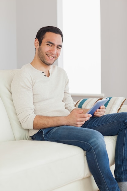 Glimlachende knappe mens die zijn tablet gebruiken