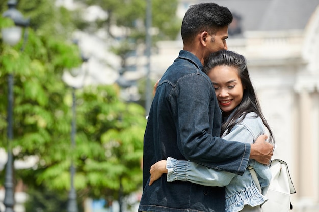 Glimlachende knuffelende jonge man en vrouw blij elkaar te zien na lange scheiding vanwege coronavirus