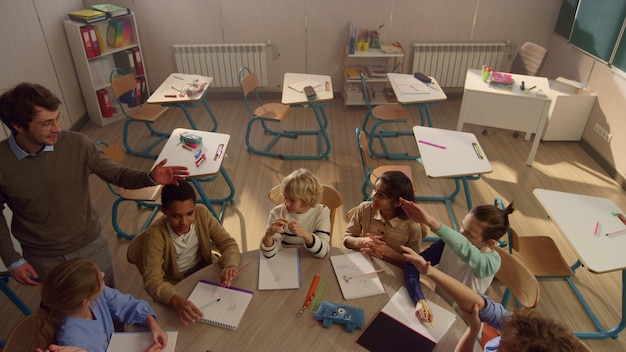 Foto glimlachende leraar legt de les uit aan studenten aan een ronde tafel