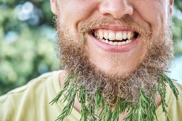 Foto glimlachende man baard en geurig takje rozemarijn volwassene gedraagt zich kinderachtig met opgewonden uitdrukking