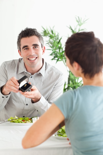 Glimlachende man die aan zijn verraste vriendin tijdens diner voorstelt