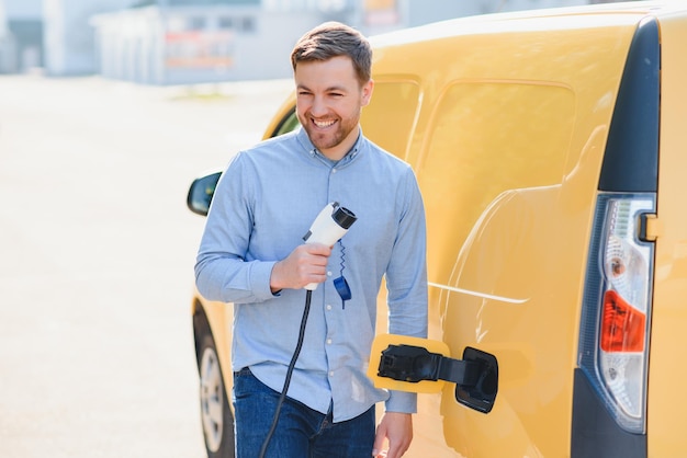 Glimlachende man die de oplader uit de auto haalt