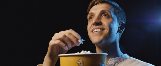 Foto glimlachende man die een film kijkt en popcorn eet