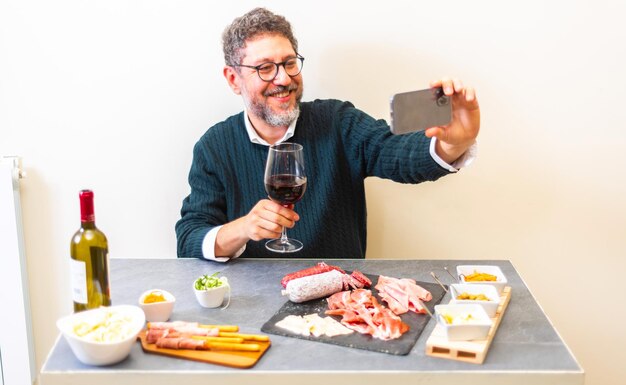 Foto glimlachende man die een selfie maakt terwijl hij een drankje vasthoudt in een restaurant