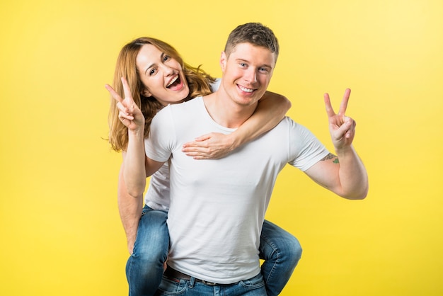 Glimlachende man die haar meisje piggyback rit maken overwinning teken