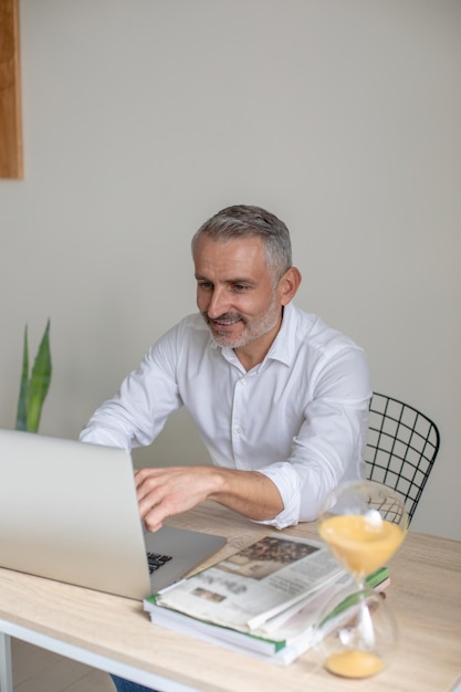 Glimlachende man die naar een laptop kijkt die op kantoor zit