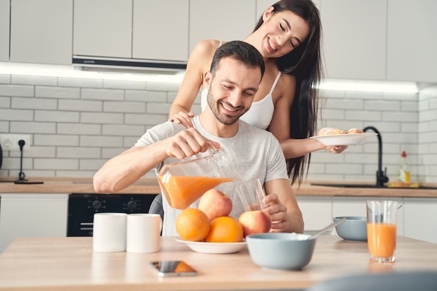 Glimlachende man en vrouw die 's ochtends samen ontbijten. vrouw brengt croissants naar haar man