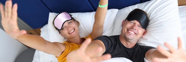 Glimlachende man en vrouw in slaapmaskers liggen op bed, comfortabel slaapconcept