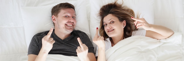 Glimlachende man en vrouw liggen in bed en bellen fak-gebaarconcept