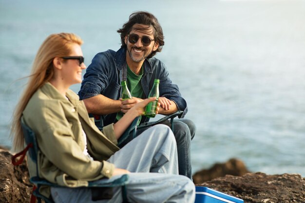 Glimlachende man en vrouw ontspannen samen op de rotsen aan de kust van de Oceaan