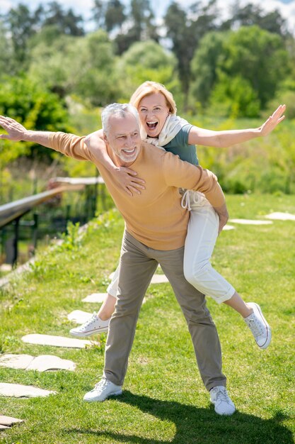 Glimlachende man geeft zijn vrouw een ritje op de rug