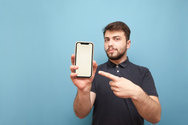 Glimlachende man houdt een smartphone in zijn handen en toont zijn vinger op een wit scherm op blauw