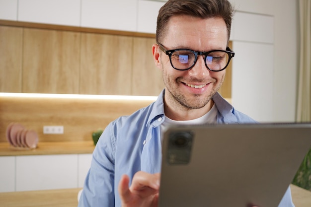 Glimlachende man in een bril met een tablet in een lichte en moderne kantoorruimte