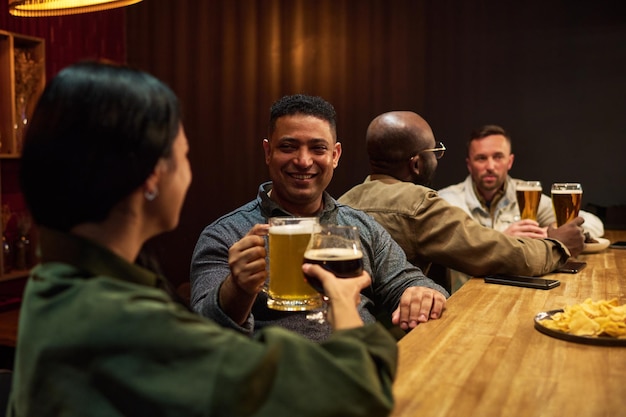 Glimlachende man met een beker schuimend bier die toast met een jonge brunette vrouw.