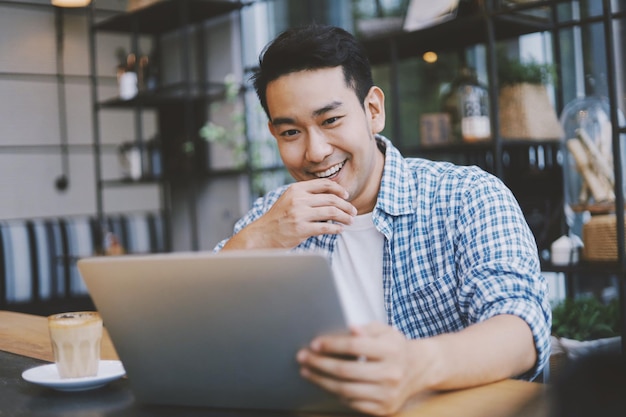 Glimlachende man met een laptop terwijl hij in een café zit