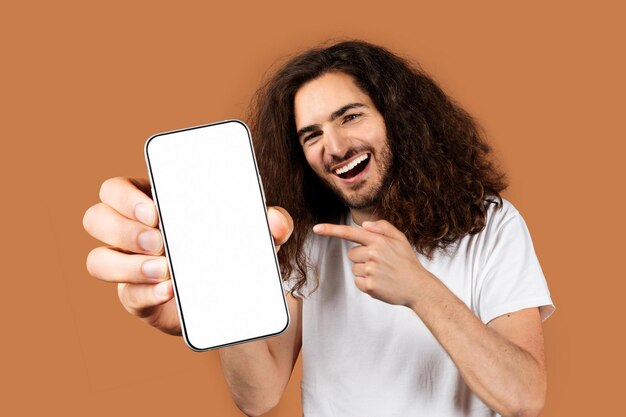 Glimlachende man met een leeg smartphone scherm tegen een beige achtergrond.