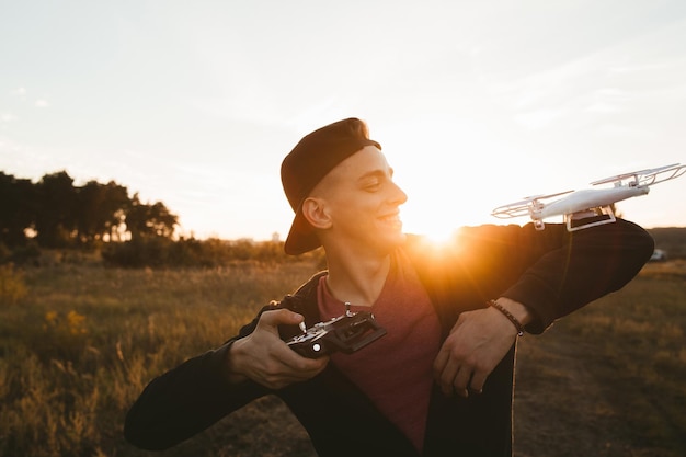 Glimlachende man met rc drone op zijn schouder zonsondergang flare Blije man landde zijn quadrocopter op zichzelf met afstandsbediening Vrije tijd leuk succes entertainment leuk concept