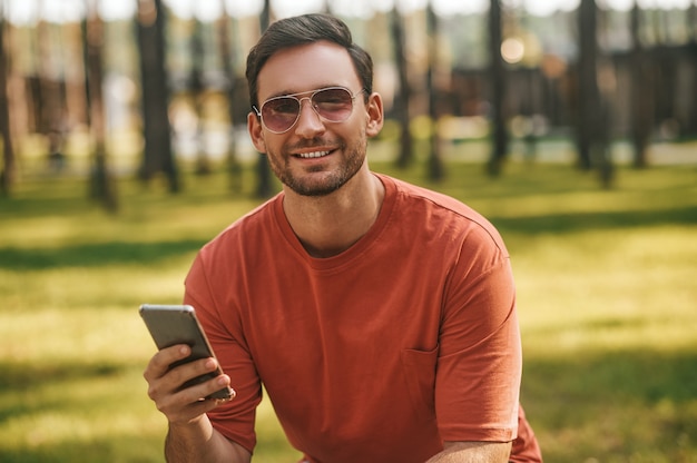 Glimlachende man met smartphone camera kijken