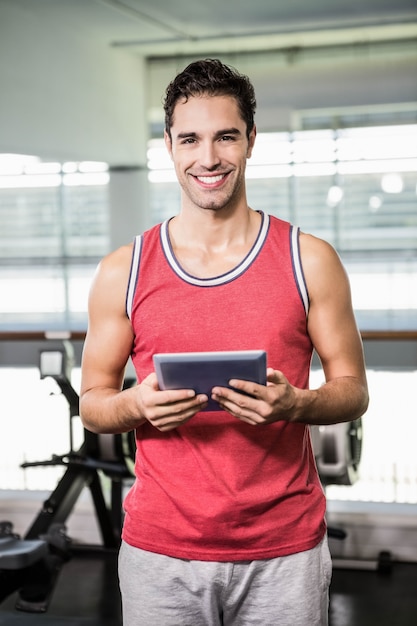 Glimlachende man met tablet in de sportschool