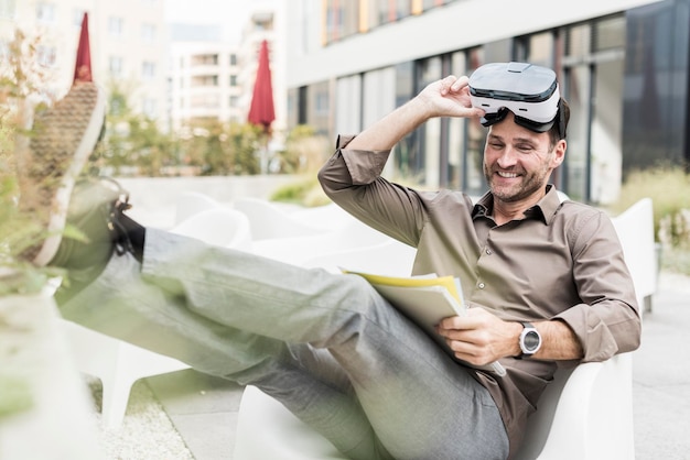 Glimlachende man met Virtual Reality Bril en documenten zittend op terras