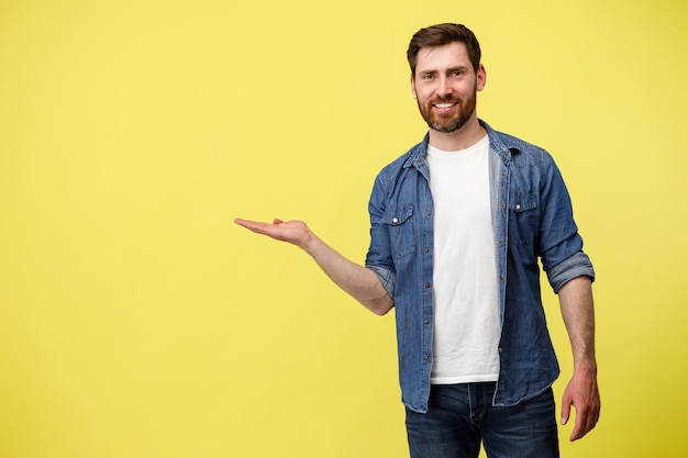 Glimlachende man staat op gele achtergrond wijst zijn vinger naar de zijkant op een lege plaats