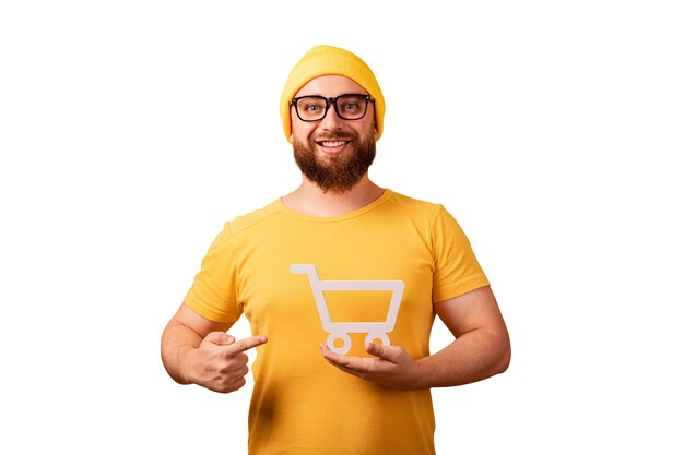 Foto glimlachende man wijst naar winkelwagentje symbool in de hand geïsoleerd op witte achtergrond zwarte vrijdag en grote verkoop concept