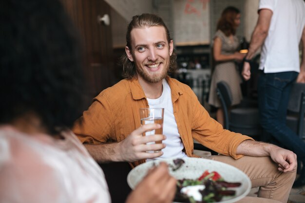 Glimlachende man zit in restaurant en praat met vrouw