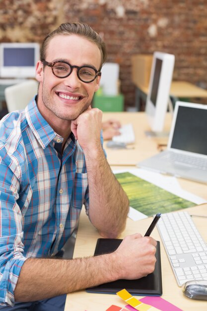 Glimlachende mannelijke fotoredacteur in bureau