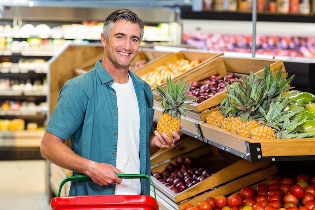 Glimlachende mens die ananas kiest