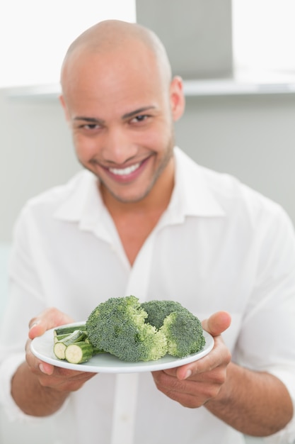 Glimlachende mens die een plaat van broccoli houdt