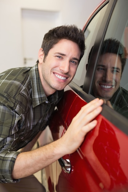 Glimlachende mens die een rode auto koestert